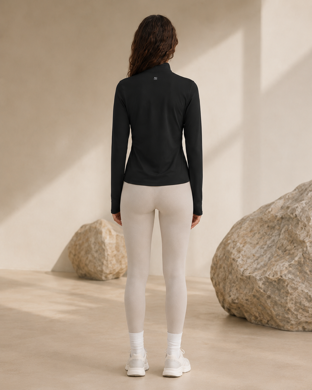 Woman wearing the NORTHE Studio Form Jacket in Black with neutral leggings, shown from the back in a minimal studio setting.