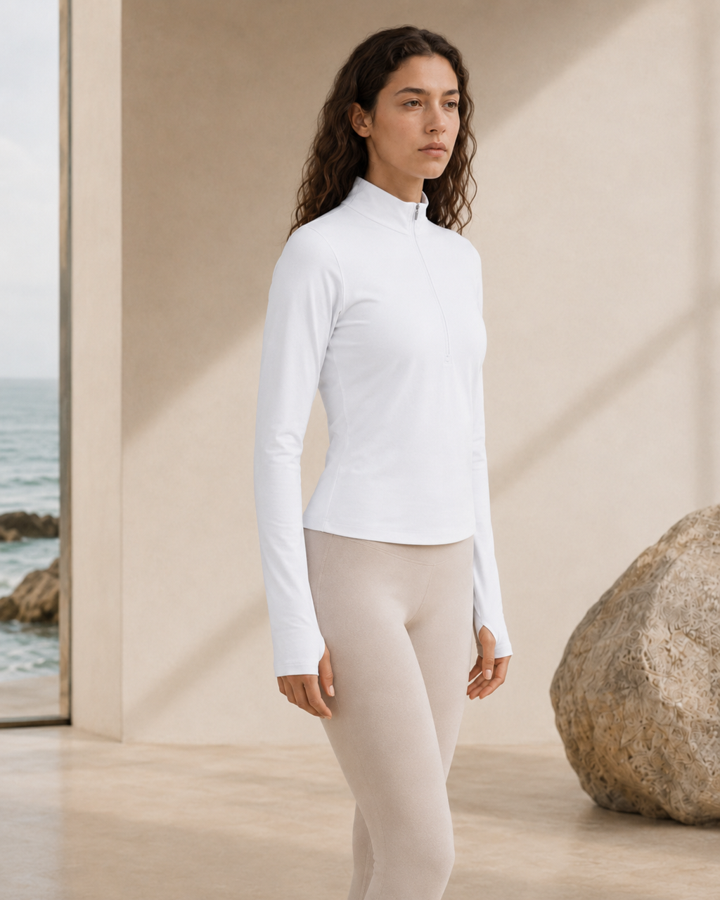Woman wearing the NORTHE Studio Form Jacket in Frost with neutral leggings, shown from the side in a minimal coastal studio setting.