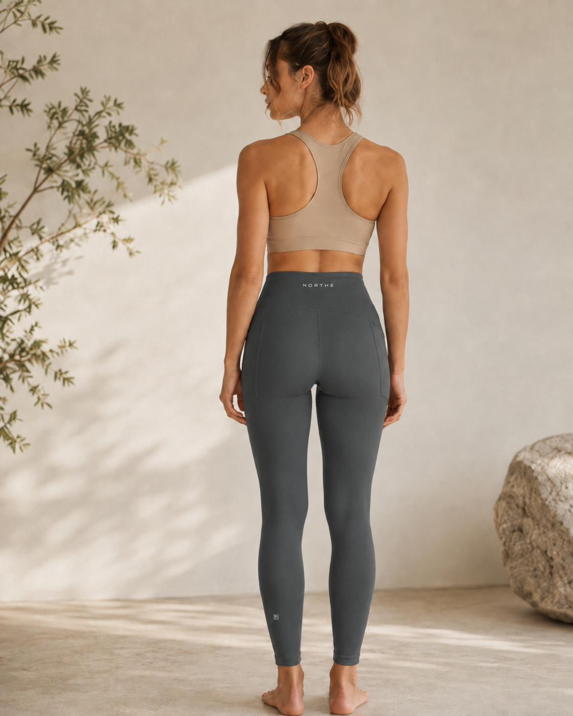 Woman wearing the NORTHE Studio Sculpt Legging in Black, shown from the back in a minimal studio setting.