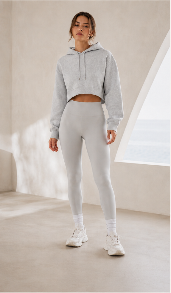 Person wearing a gray hoodie and leggings set in a minimalistic room.